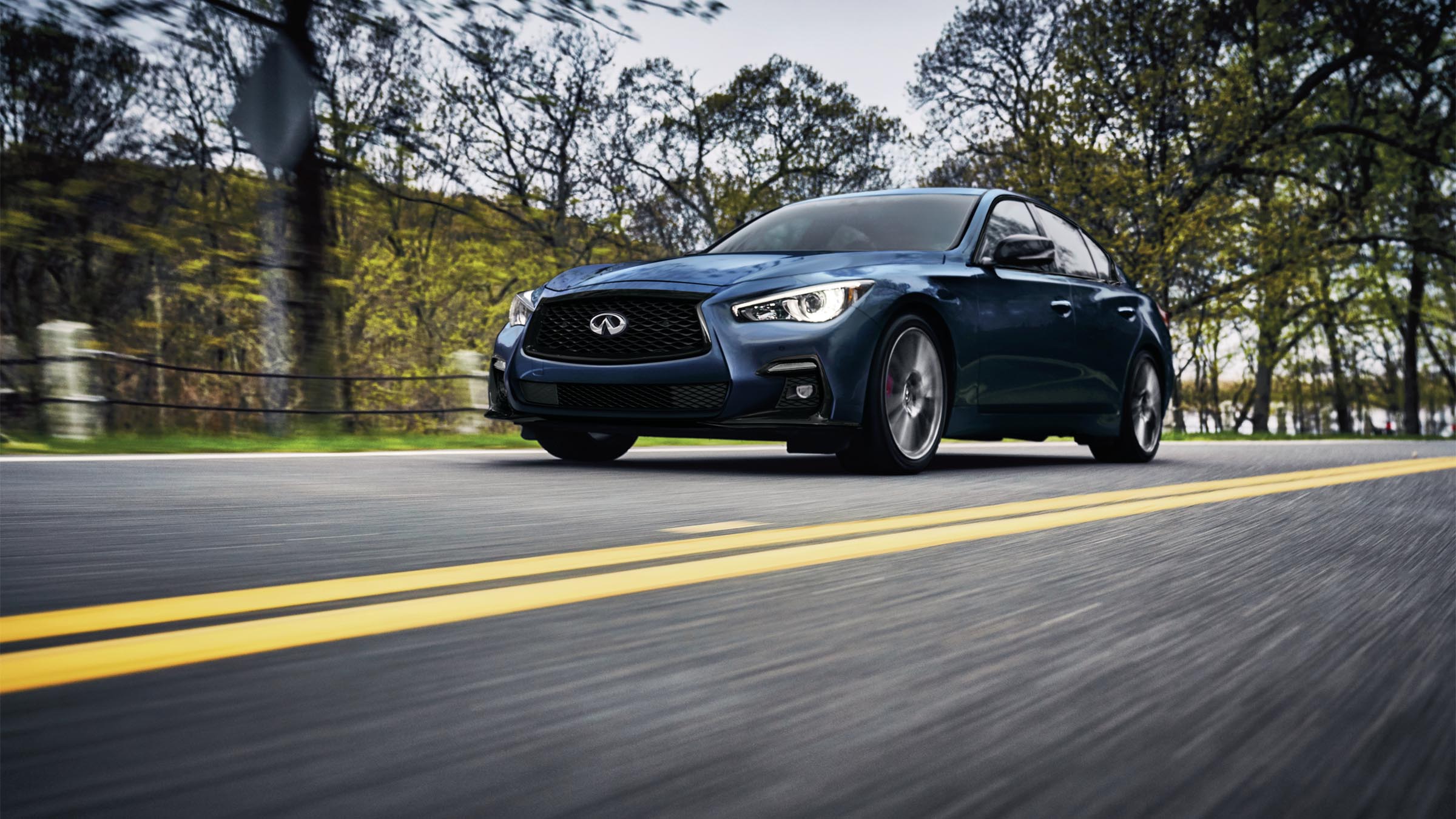 Exterior view of a blue 2022 INFINITI Q50 sedan on the road.